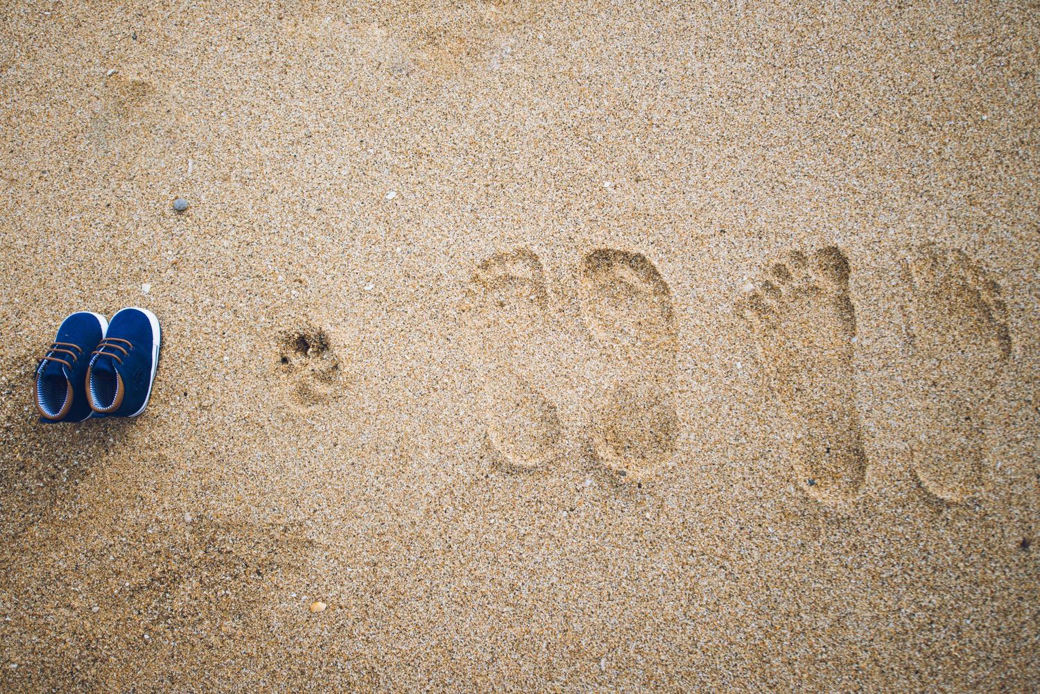 Empreintes de pas dans le sable avec sandales bleues sur une plage en Bretagne, détail poétique d’un mariage en bord de mer.