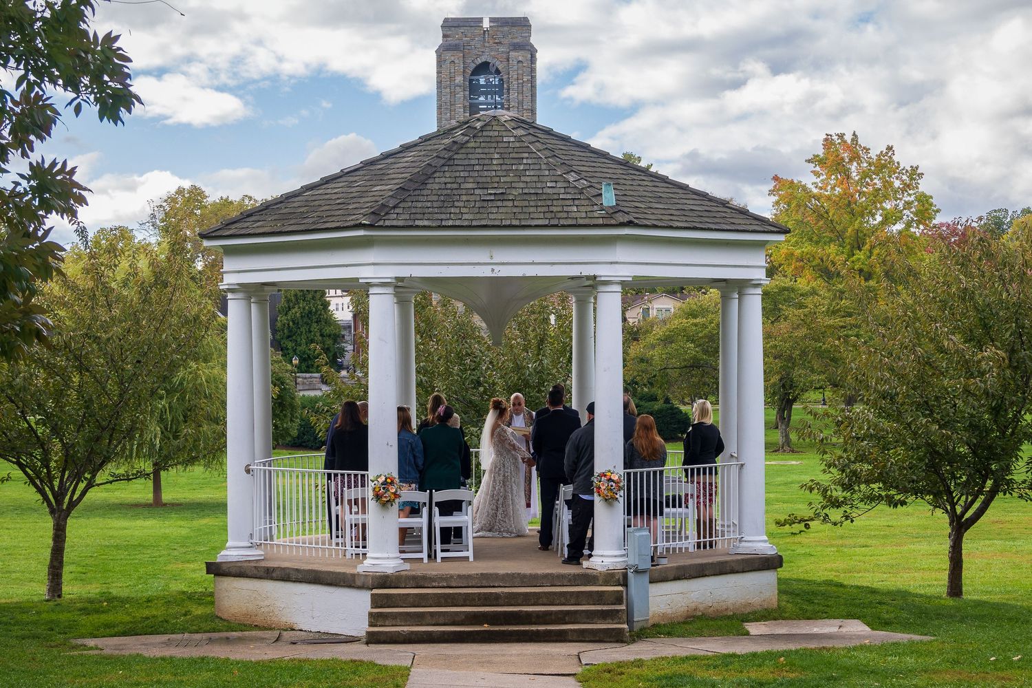 frederick maryland wedding photographer Wedding ceremony takes place in white gazebo surrounded by green lawn and trees.