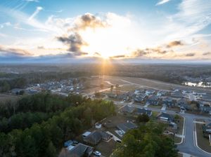 Aerial panorama of suburban neighborhood during sunset with golden sky and residential streets.
