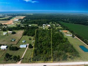 Aerial view of rural property with yellow boundary markers along main road and wooded areas.