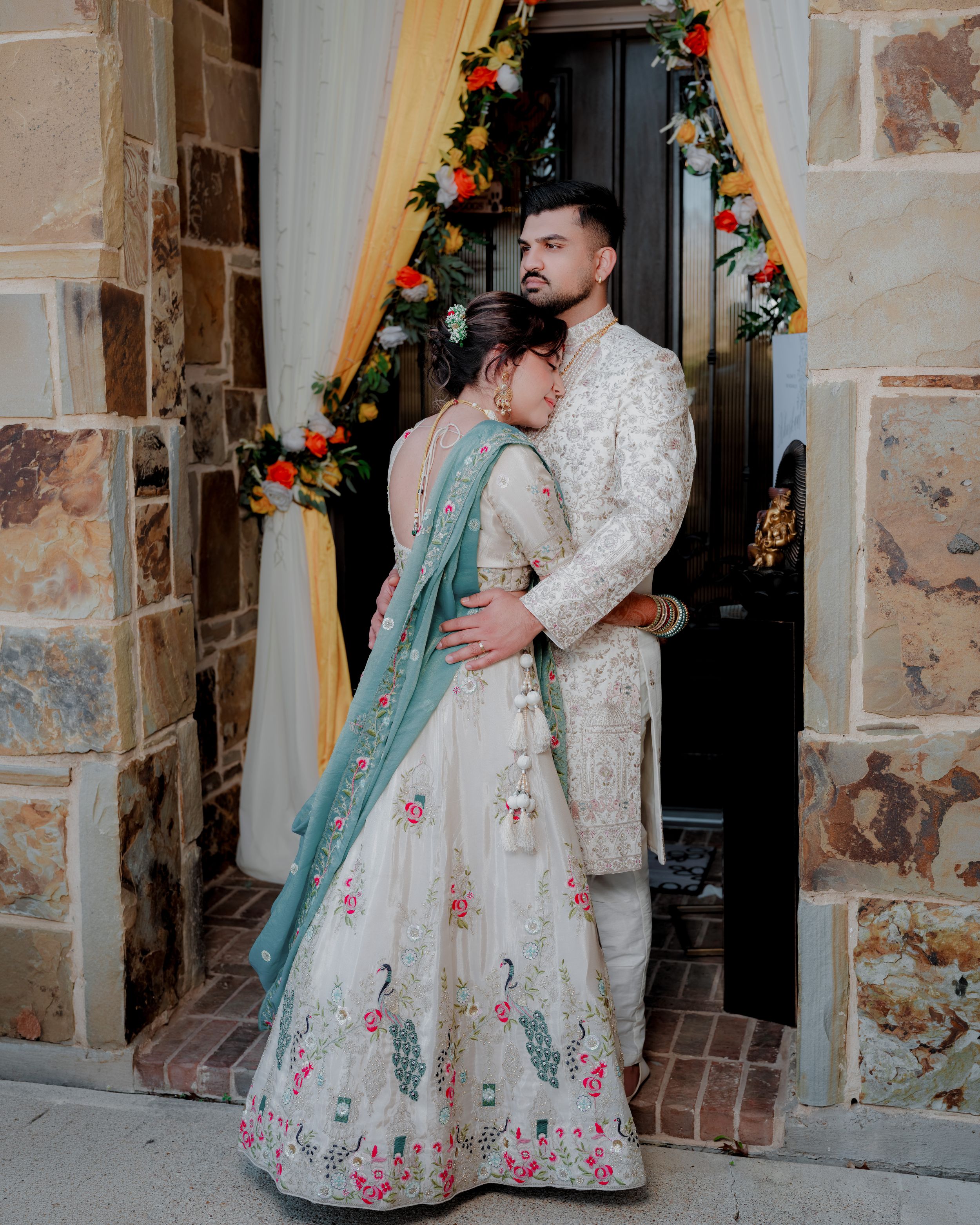 Romantic dance scene in vintage-style clothing against stone wall with colorful floral decorations.