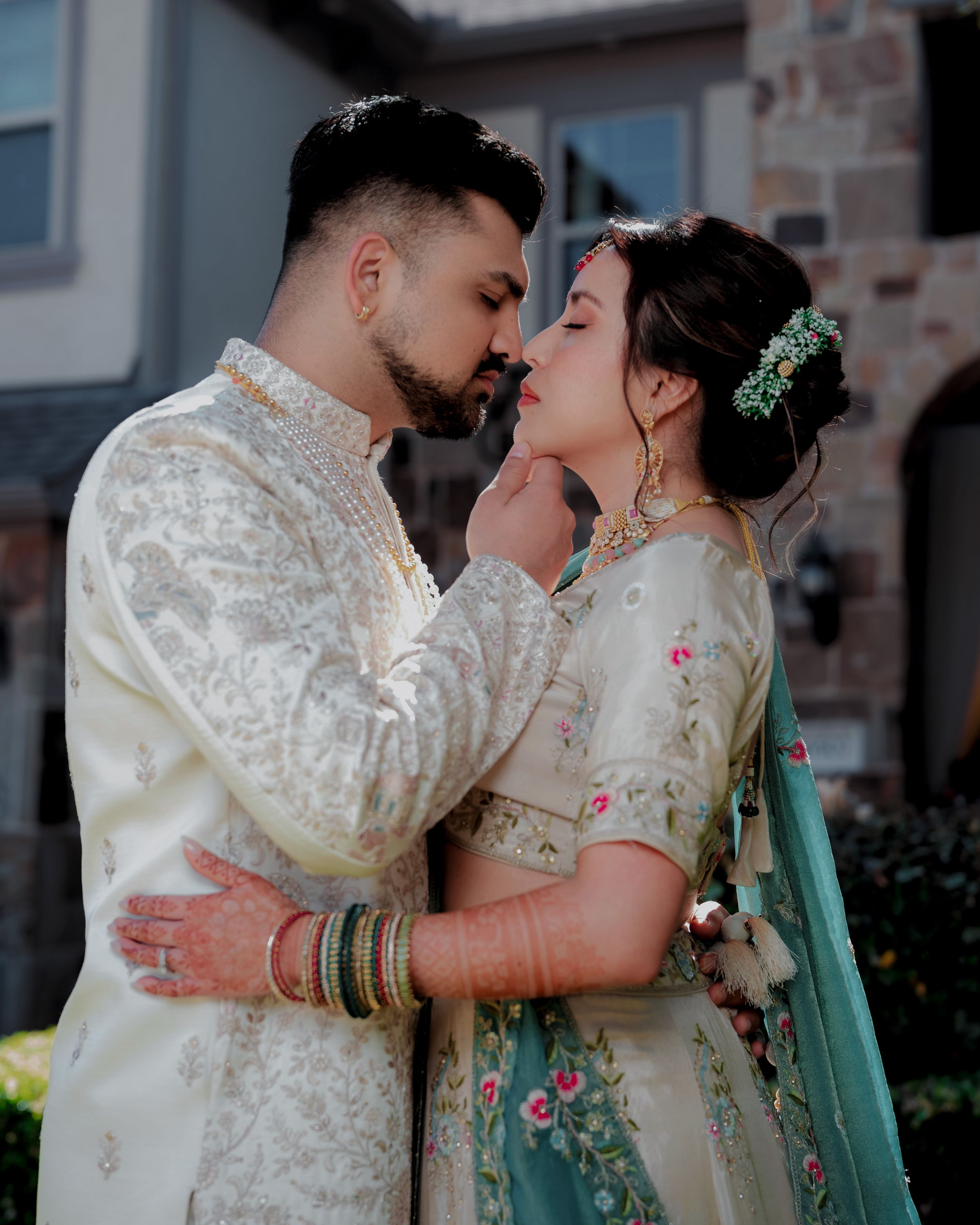 A couple in traditional South Asian wedding attire share romantic moments in a series of outdoor portraits.