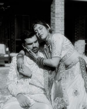 Black and white romantic portrait of a couple in traditional South Asian wedding attire.