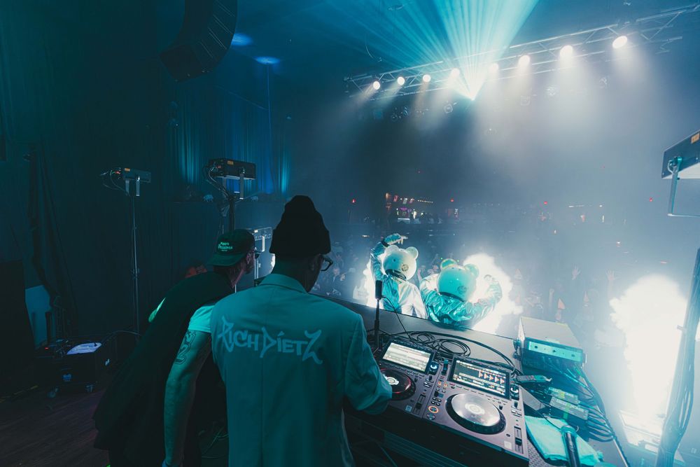DJ performs at a nightclub with dramatic blue lighting and fog effects creating an atmospheric electronic music environment.