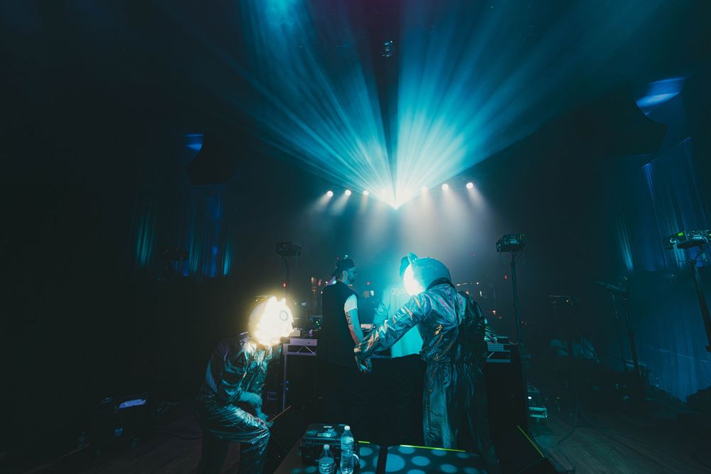 Concert stage illuminated with dramatic blue lighting and bright spotlights creating an atmospheric performance environment.