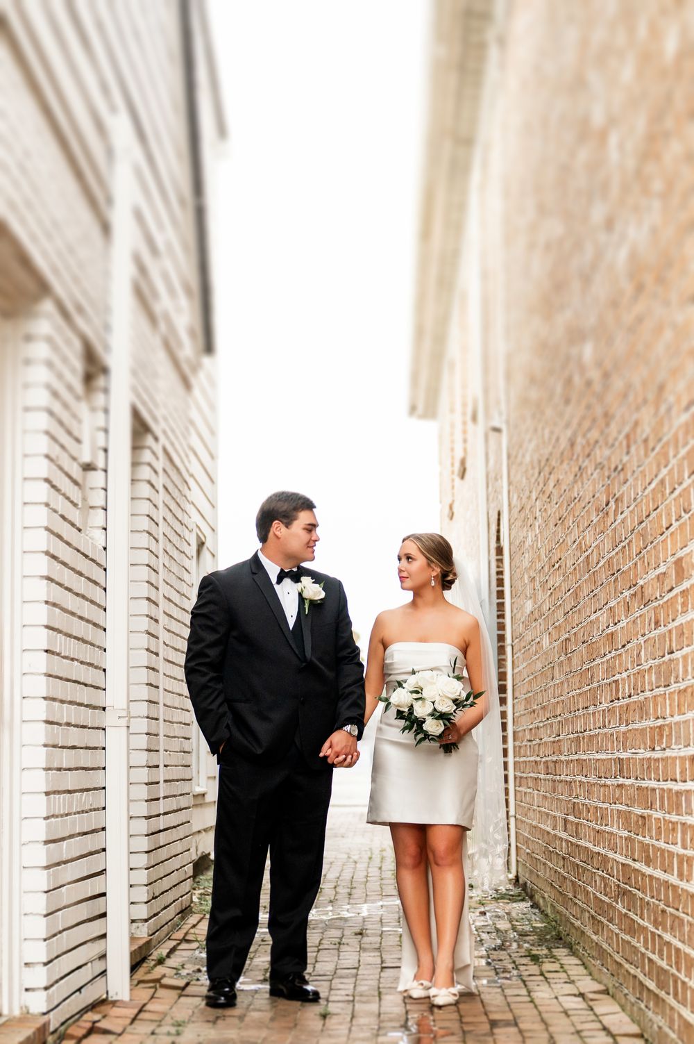 Wedding couple poses in brick corridor during intimate photo session.