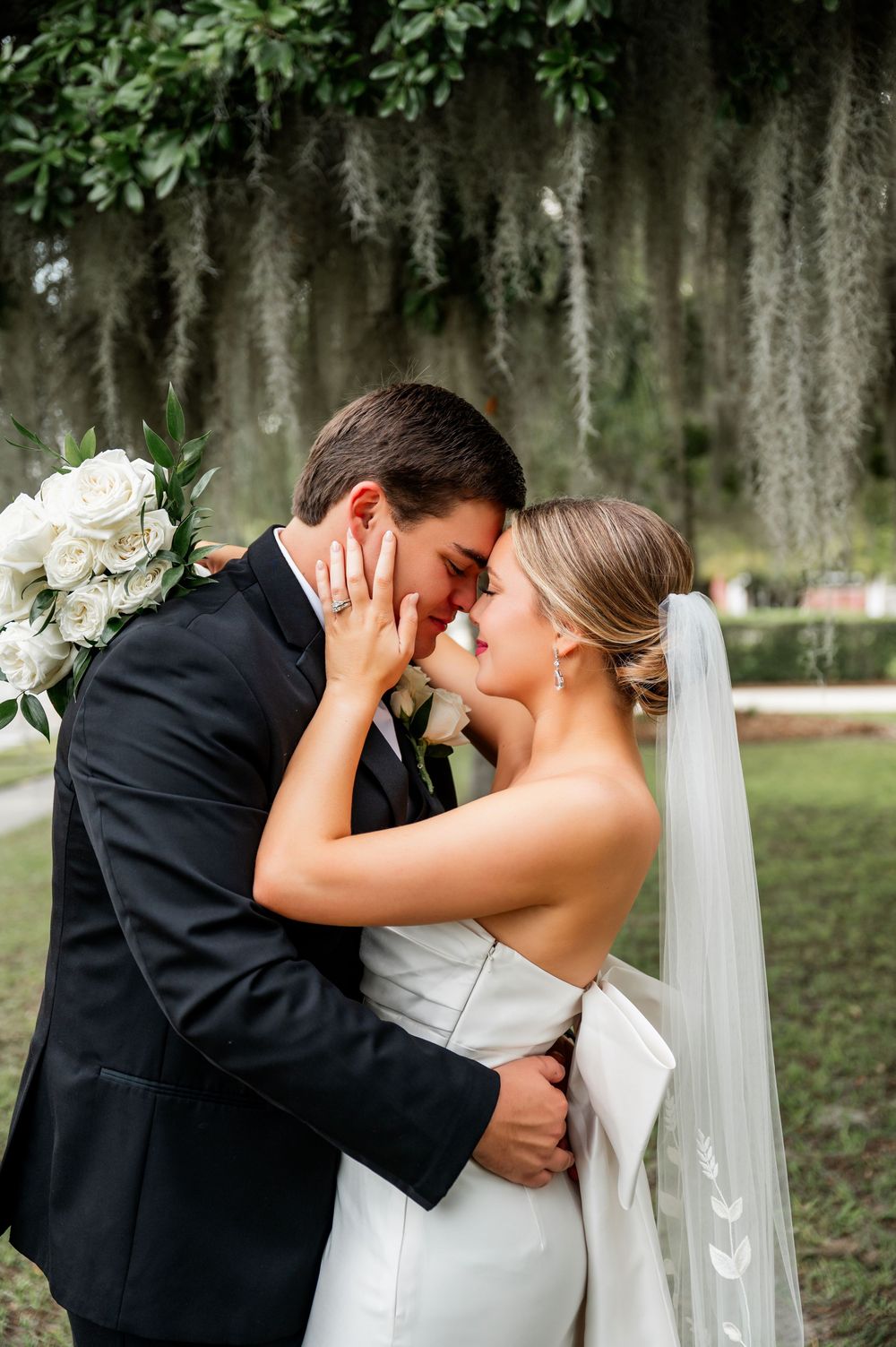 Romantic wedding portrait under Spanish moss with white floral bouquet.