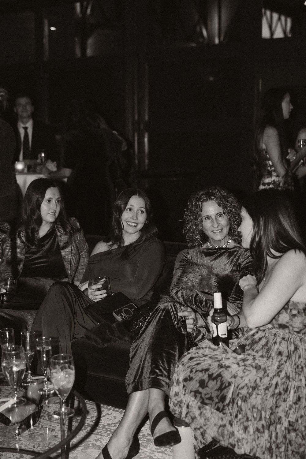 Black and white photos show people gathered at a dimly lit restaurant table enjoying drinks and conversation.