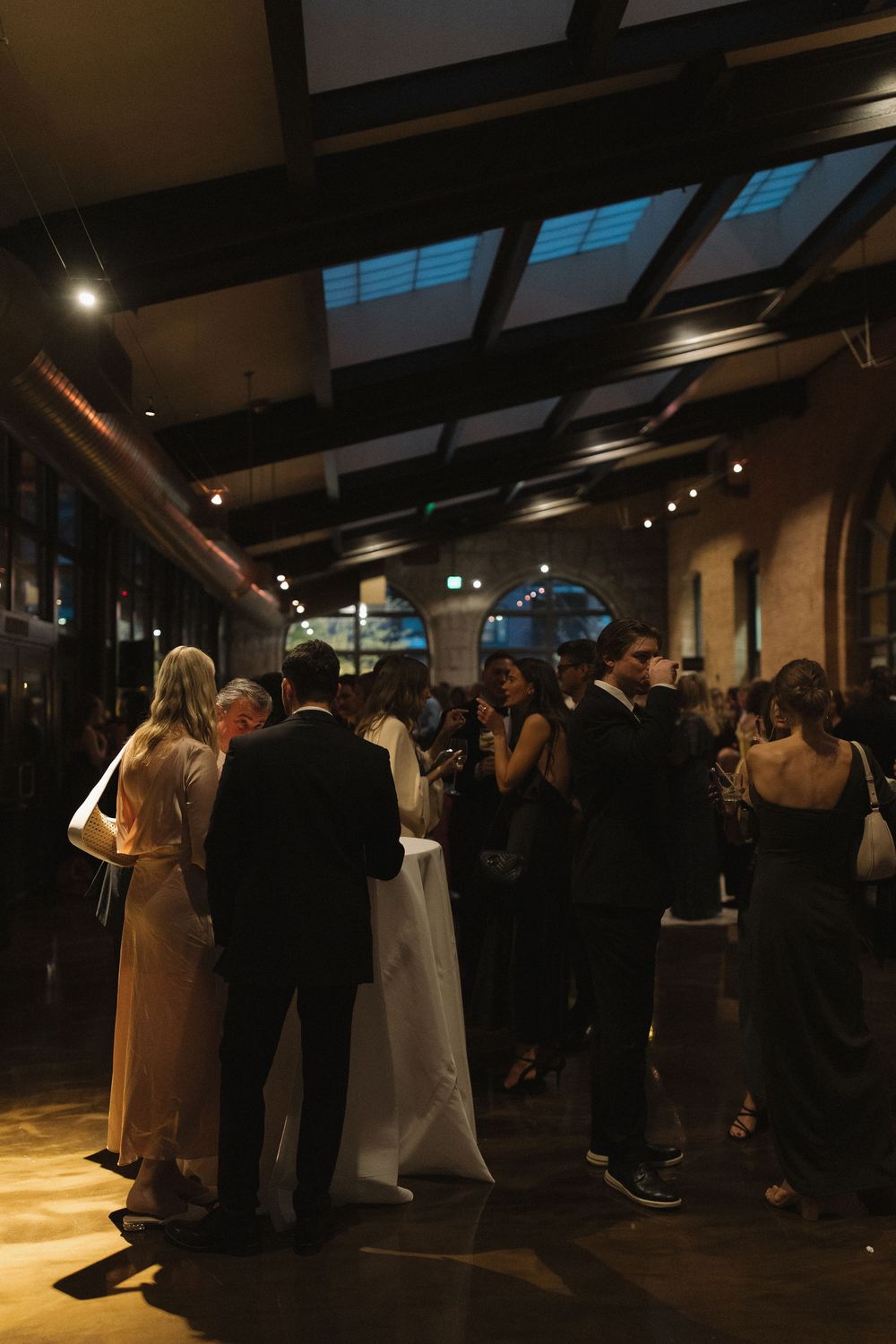 People dancing and socializing at a dimly lit indoor venue with dark ceilings and mood lighting.