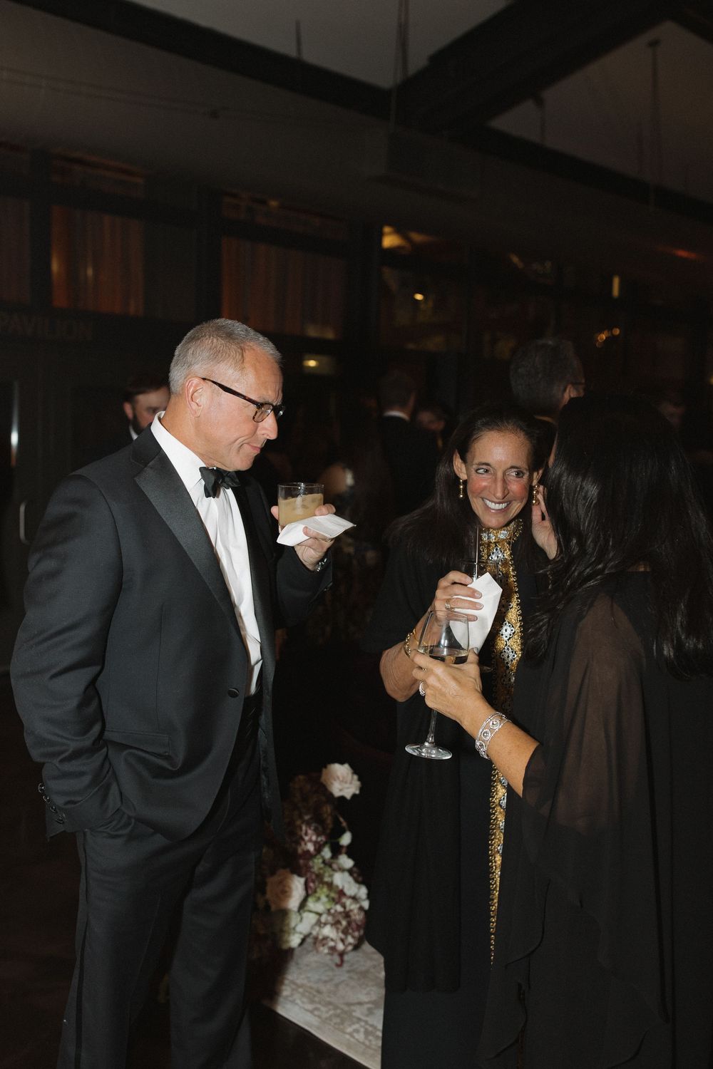 Guests in formal attire enjoying drinks and conversation at an elegant evening event.