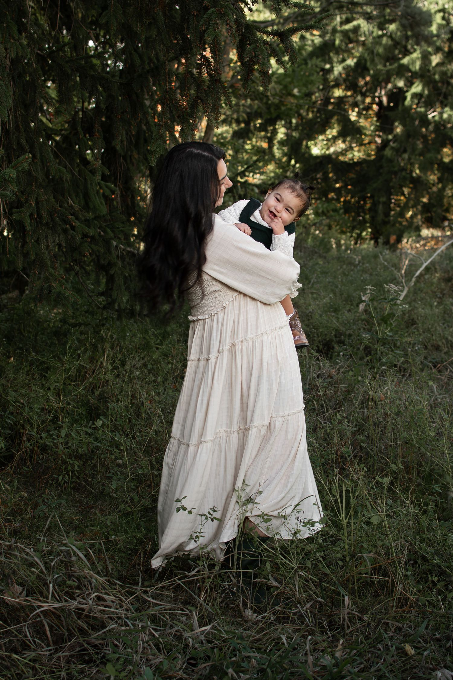 Mother holding baby girl while they sway and dance in a wooded area in Buffalo, NY