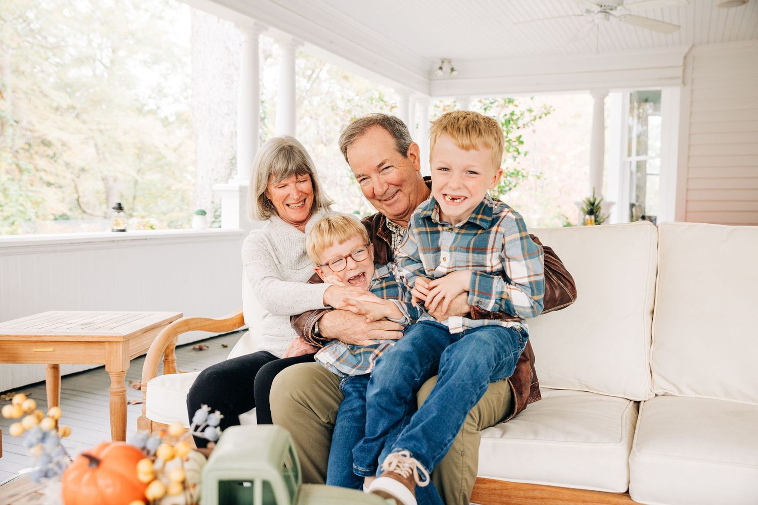 Grandparents laughing and hugging grandchildren on front porch in Charlotte,NC
