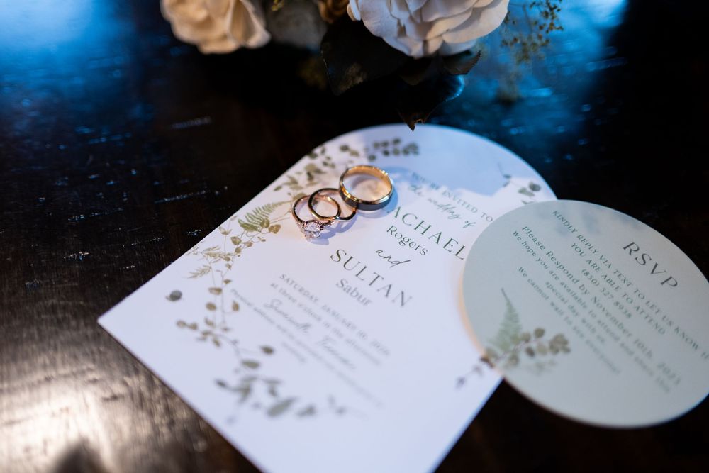 Elegant wedding invitation suite with floral designs and gold accents displayed in multiple angles on dark background.