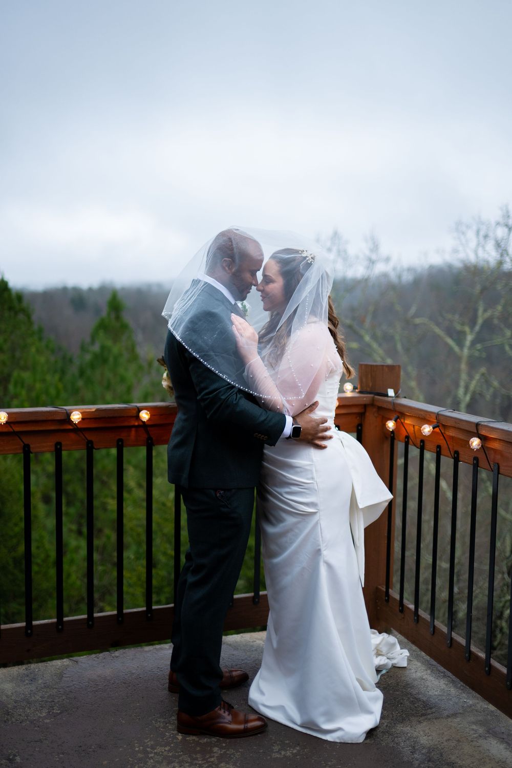 Romantic couple sharing intimate moments on a wooden deck overlooking a misty mountain landscape.