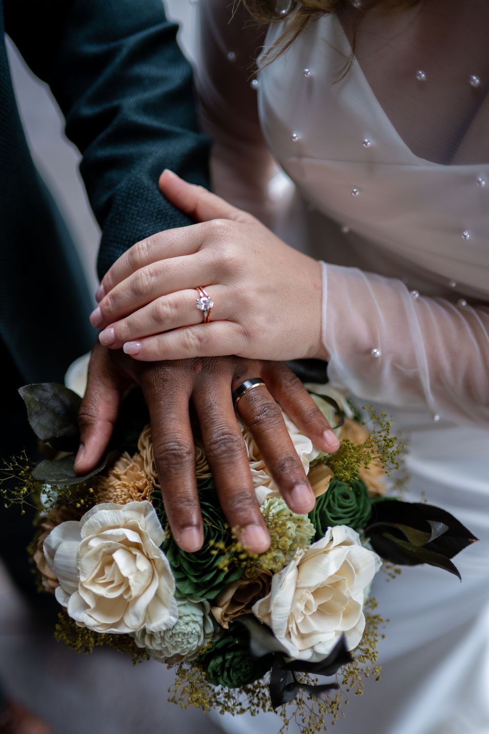 Close-up series of wedding rings and white roses with hands resting on white fabric in romantic wedding photography.