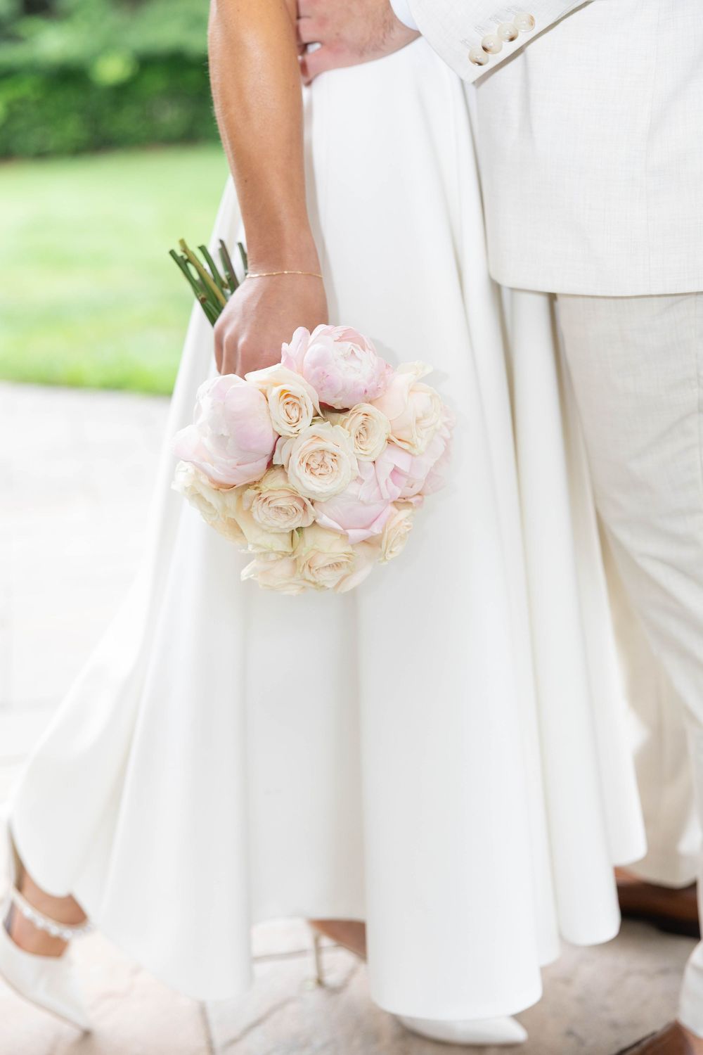 Close-up shots of pink and cream wedding bouquets held against white formal attire.