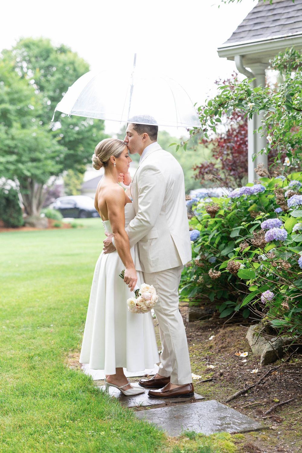 A couple shares a romantic moment in a garden setting with blooming hydrangeas and greenery.