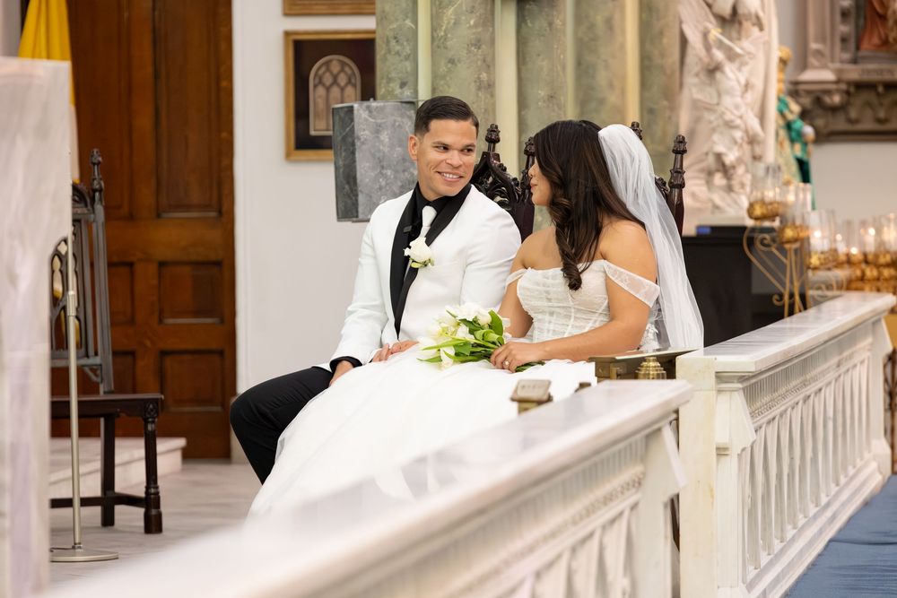 Wedding ceremony taking place in a beautiful church with marble altar and stained glass windows.