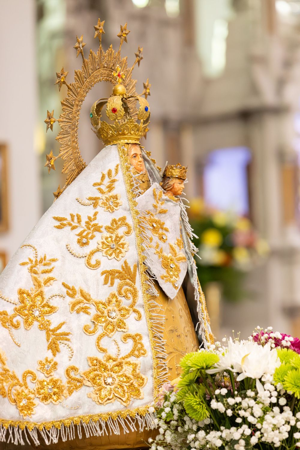 Ornate gold and white ceremonial crown with intricate floral patterns and religious symbols.