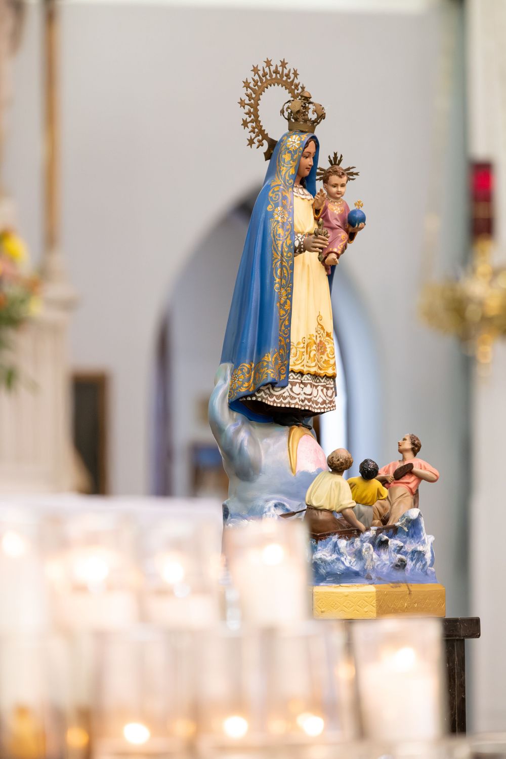 Religious figurines and candles create sacred ambiance at wedding ceremony altar.