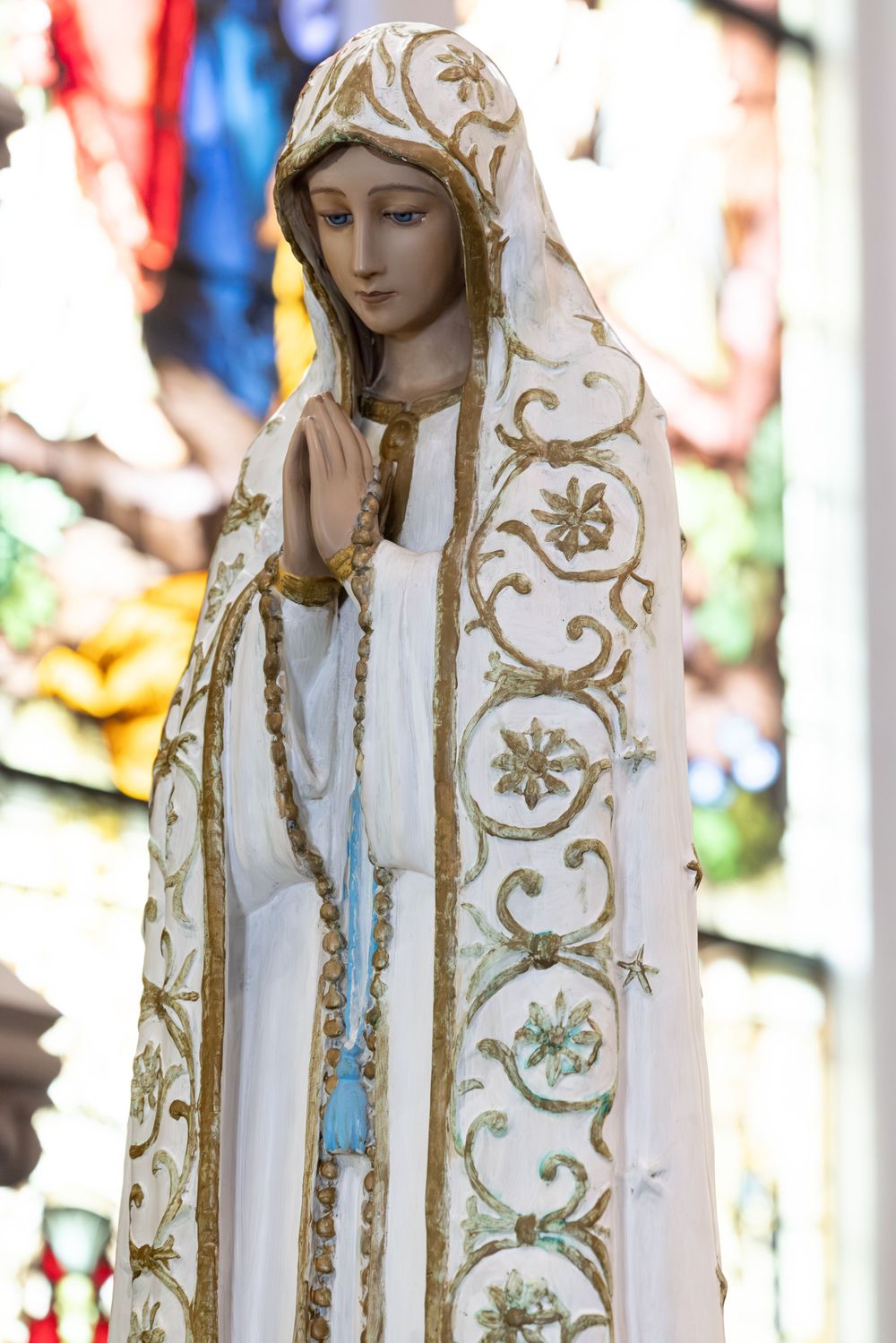 A religious statue of Mary wearing ornate white and gold robes.