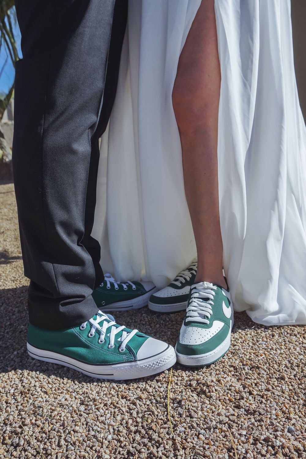 A couple wearing matching green Converse sneakers with formal wedding attire.