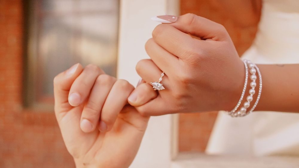 Close-up of hands with jewelry reaching toward each other.
