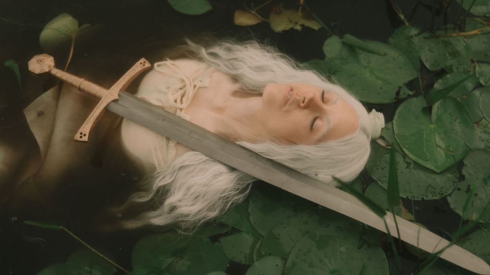 Elven fantasy woman with long white hair floating in a pond full of lilypads with a battle sword across her chest