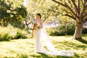 A couple shares a romantic moment in a sunlit garden setting while wearing elegant wedding attire.