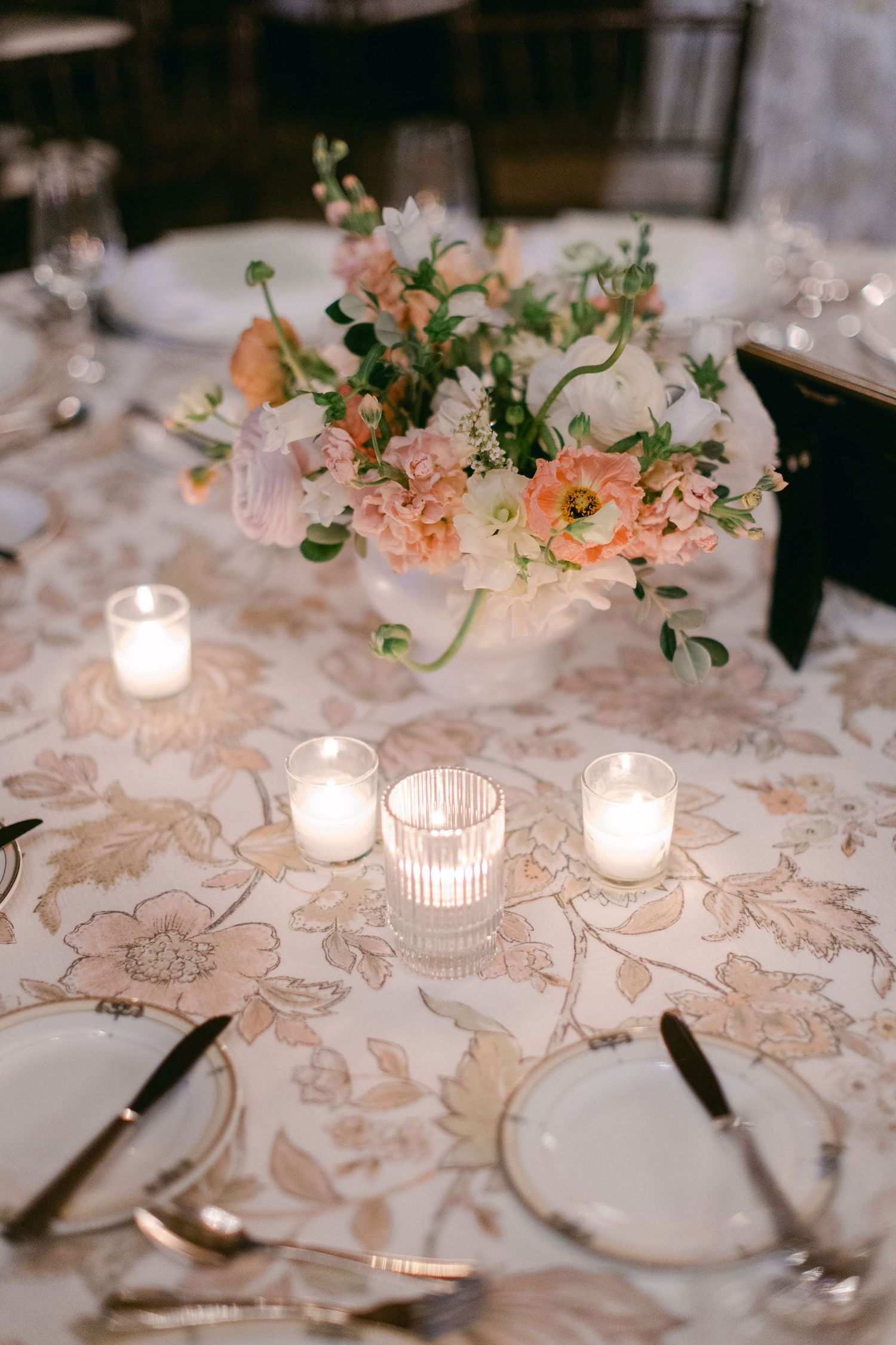 Elegant floral aisle decorations with peach roses and greenery line up alongside white wedding ceremony chairs outdoors.