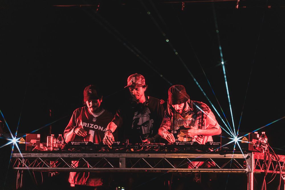 A concert crowd silhouetted against red stage lighting and blue laser beams during a live performance.