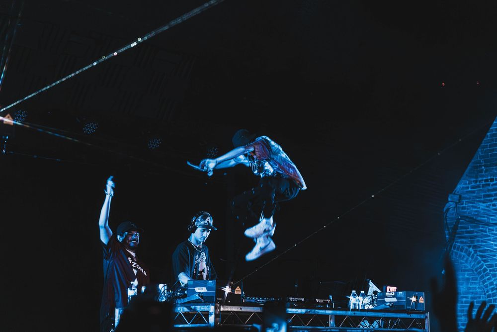 A dramatic concert performance scene bathed in blue lighting with silhouettes of performers on stage.