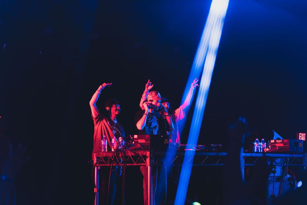 Concert performers on stage illuminated by dramatic blue and red lighting effects during a live music performance.