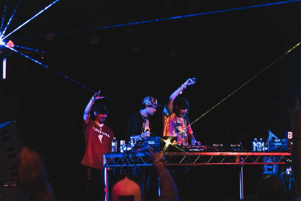 Concert performers on stage illuminated by blue lighting create an energetic atmosphere during a live music show.