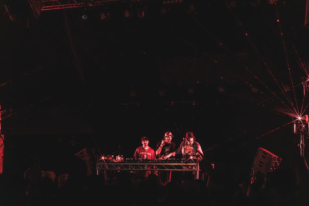 DJs perform on stage at a nightclub with red lighting and dark atmosphere during an electronic music event.