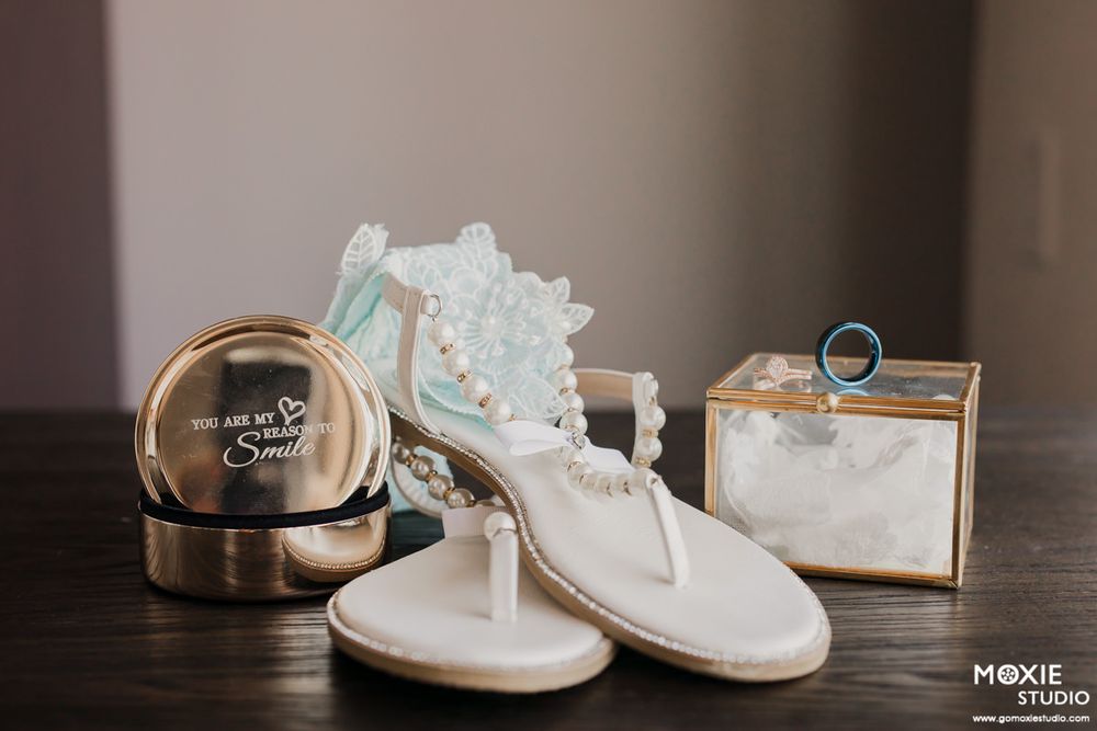 Wedding rings and white baby shoes arranged on a wooden surface with soft lighting and neutral tones.