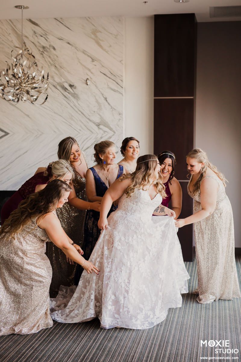 A sequence of photos showing bridesmaids in sparkly dresses helping adjust a white wedding gown on a carpeted floor.