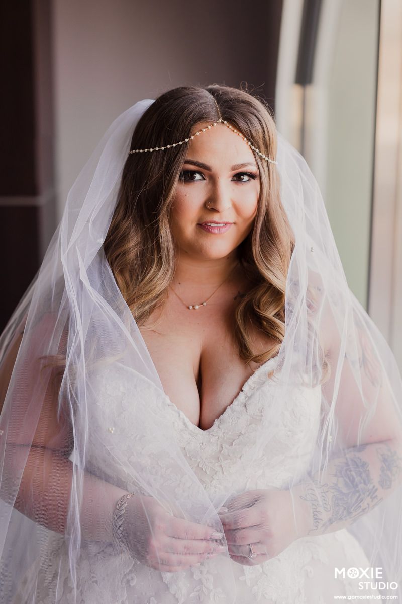 Elegant bride wearing a lace wedding gown with delicate beaded headpiece and flowing veil.