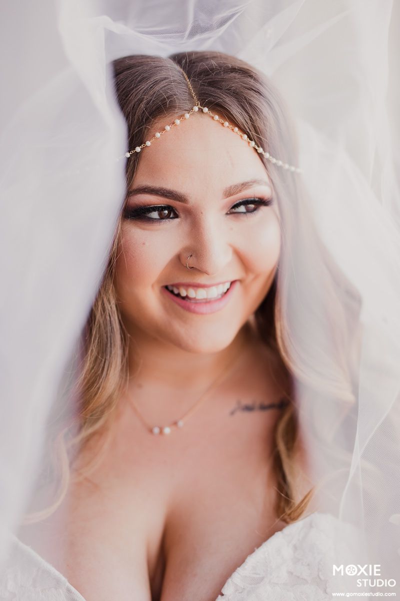 Romantic bridal portraits with soft tulle veil and natural makeup in studio setting.