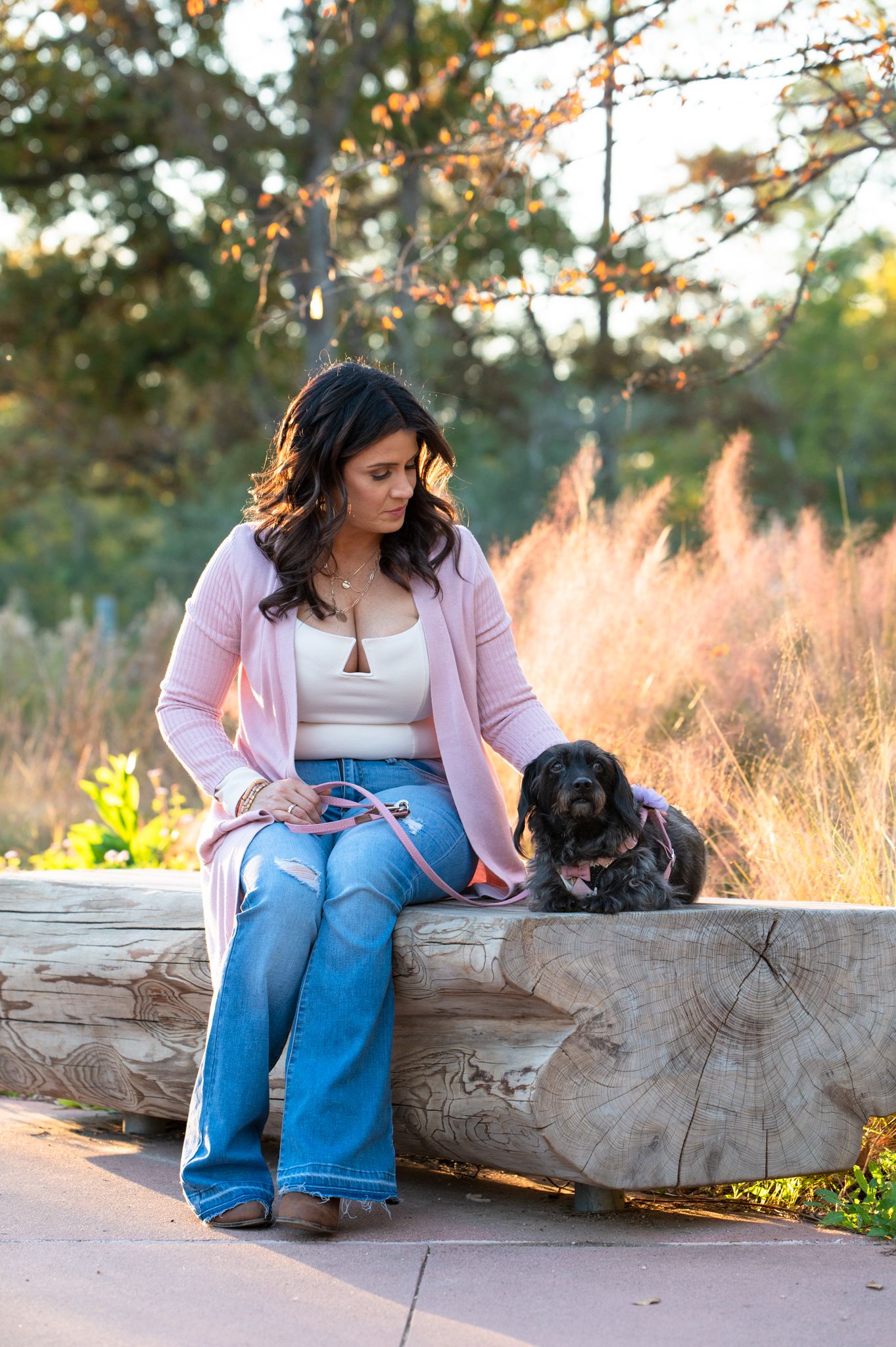 Woman sitting gently petting her black dog during golden hour pet photography session in Houston