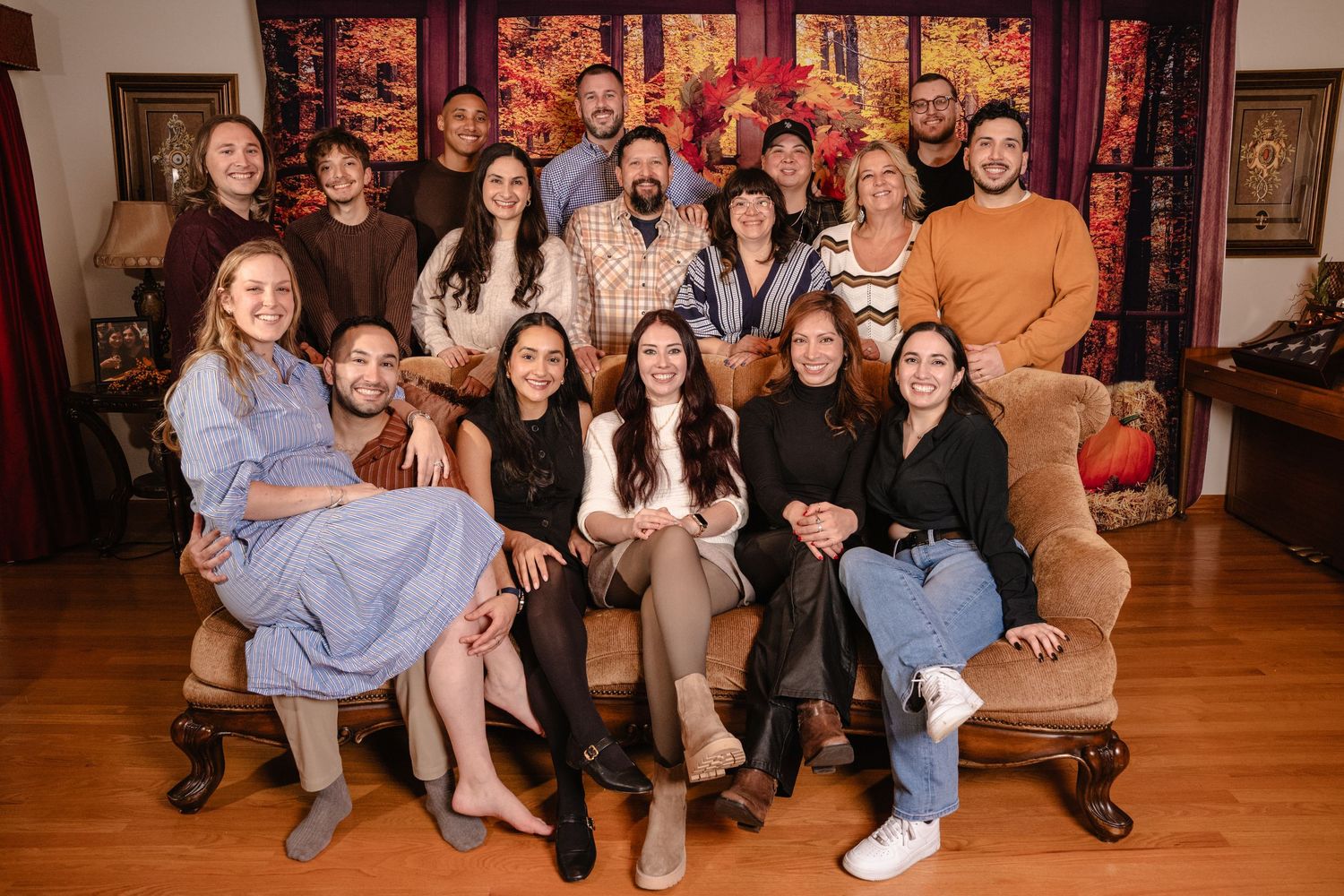 Large group of friends and family posing together for a portrait in a warmly decorated autumn room.