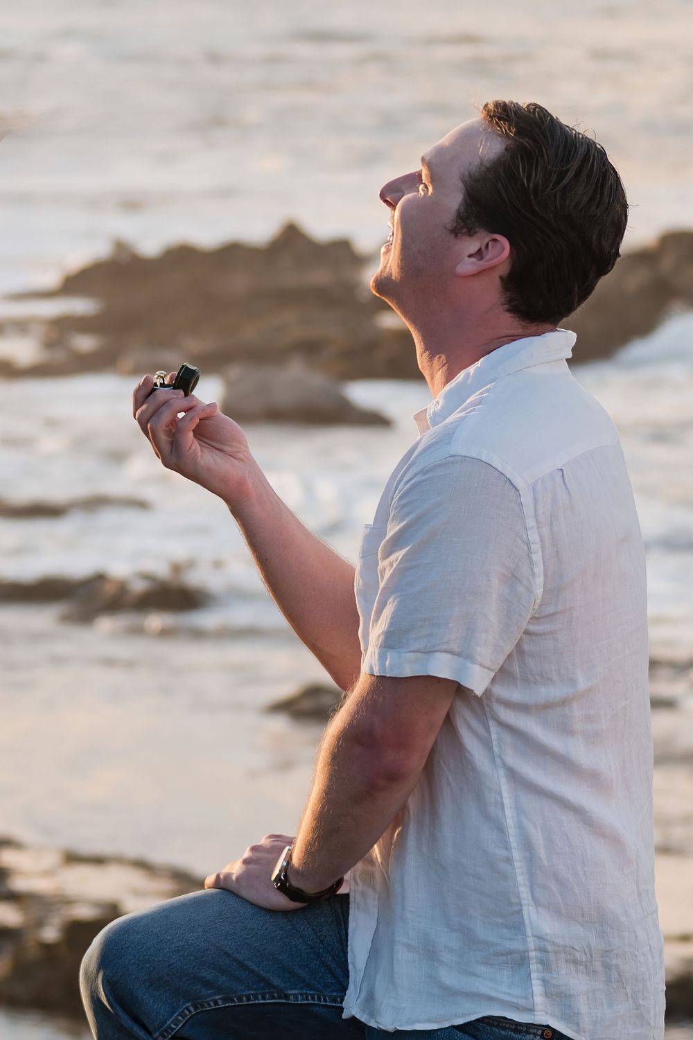 Man kneeling during surprise proposal on rocky beach in Puerto Rico