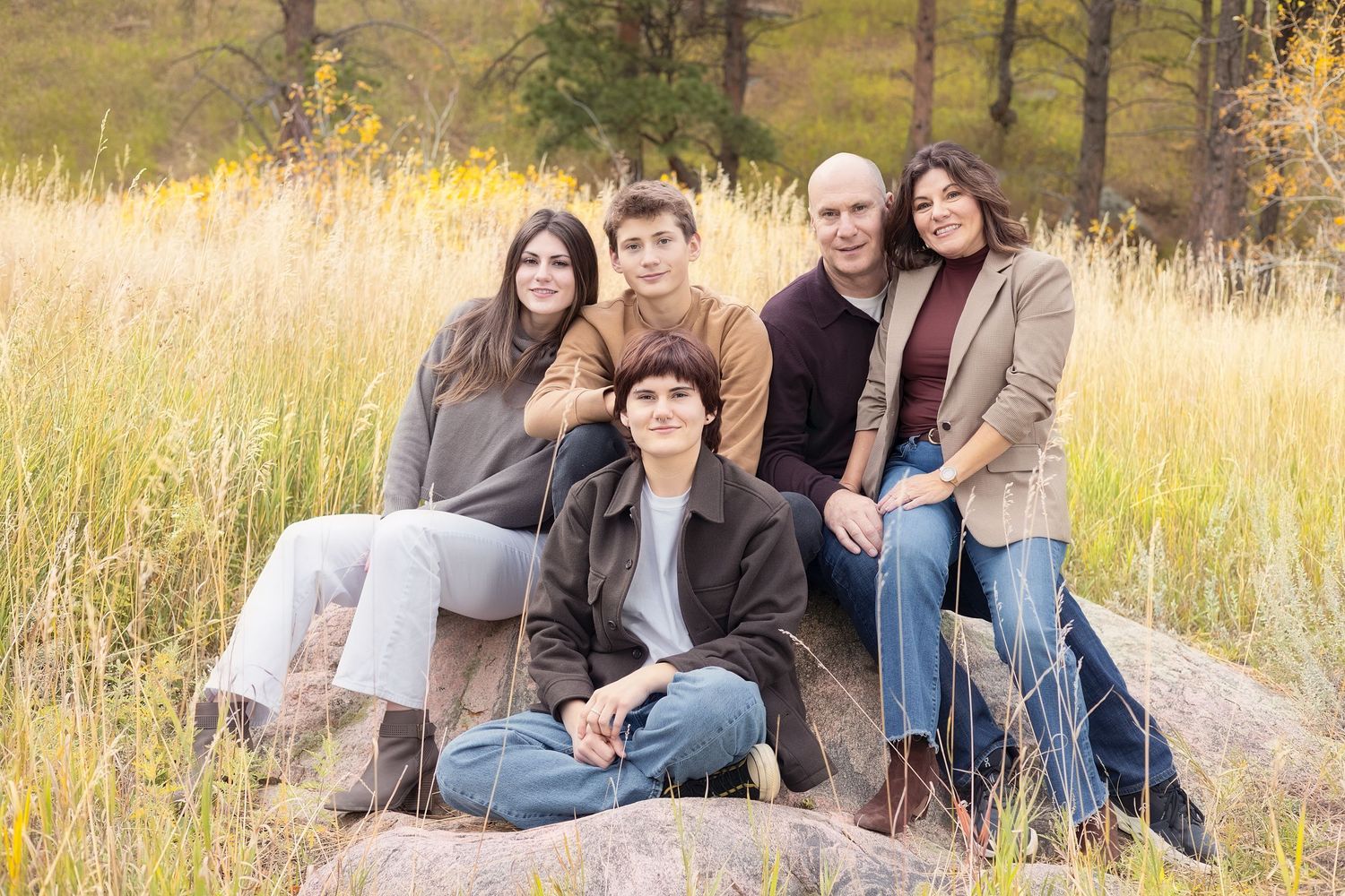 Group of people sitting together in a golden field during sunset creating a warm and intimate outdoor portrait series.