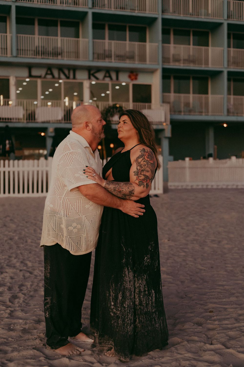 A romantic couple sits together on a sandy beach at sunset sharing intimate moments in a sequence of photos.