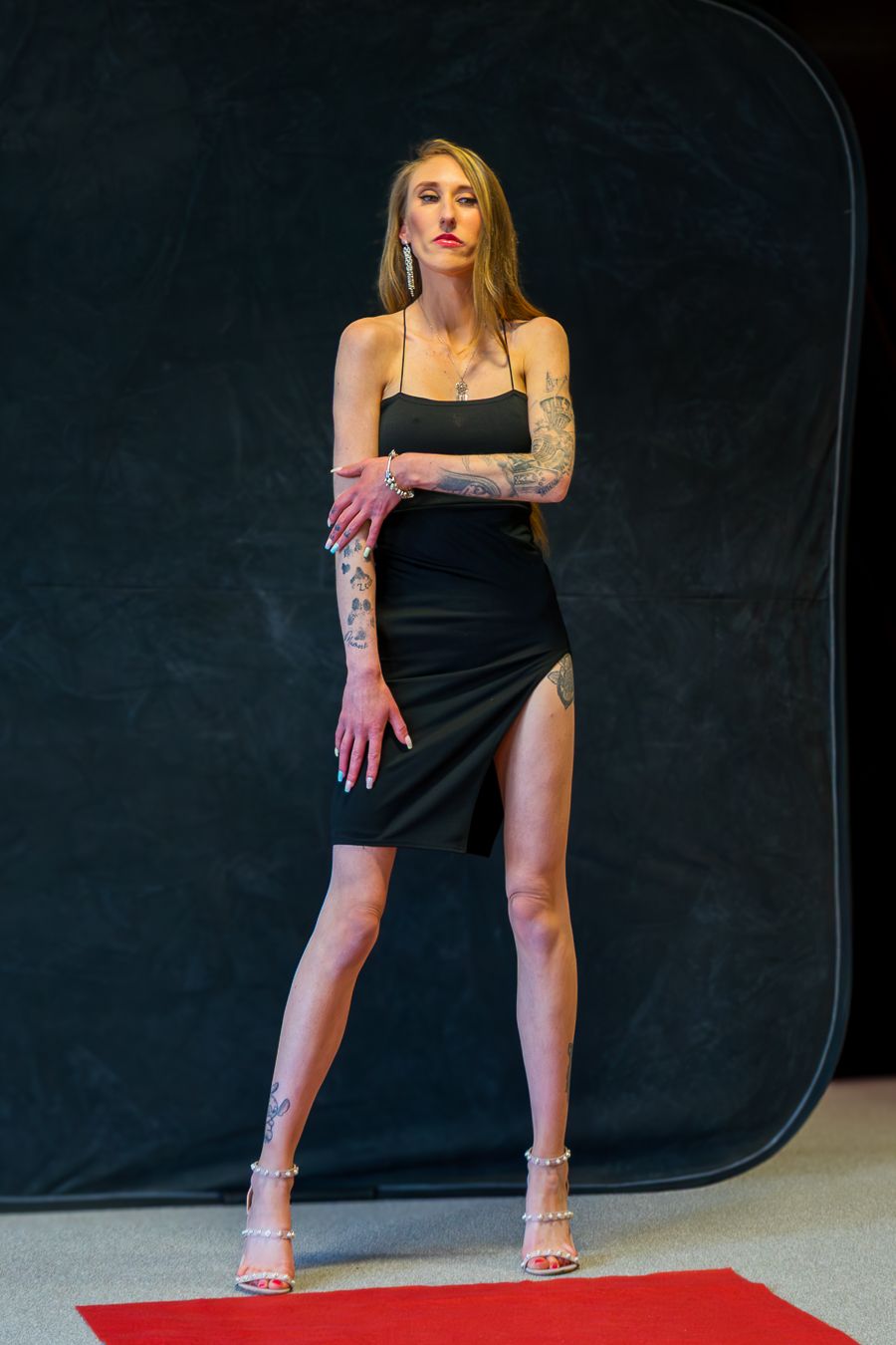 Woman in black dress poses on red carpet in dramatic fashion photography sequence.