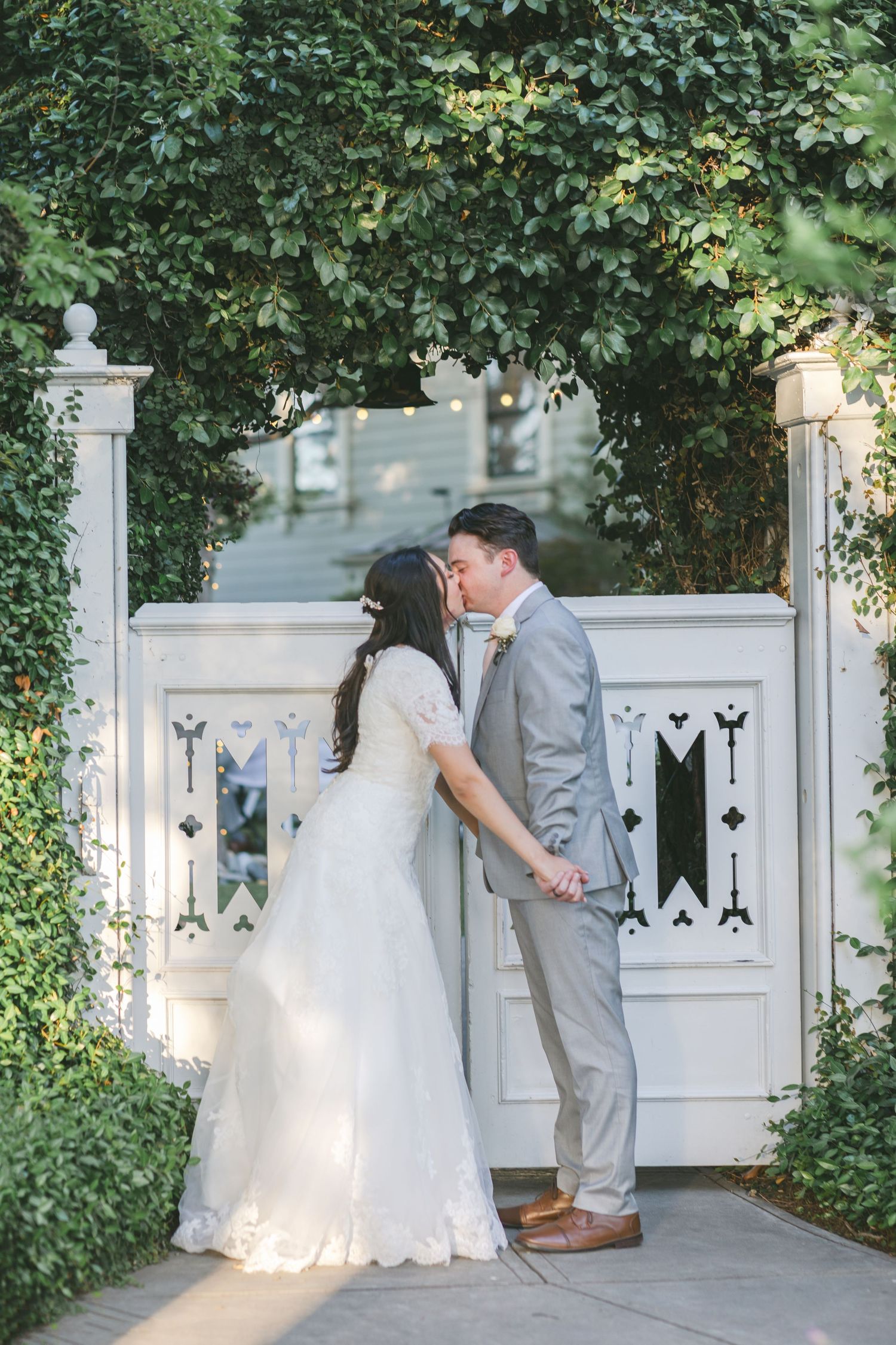 Kissing by the garden gate at McHenry Mansion Wedding Venue in Modesto California captured by Chelsee Rawe Photography