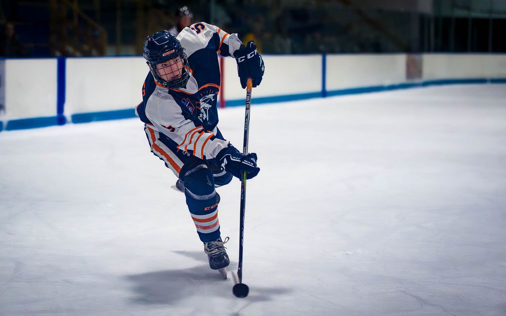 Trojans player in mid-stride, skating forward while handling the puck by SportsFox Photography, Hershey,