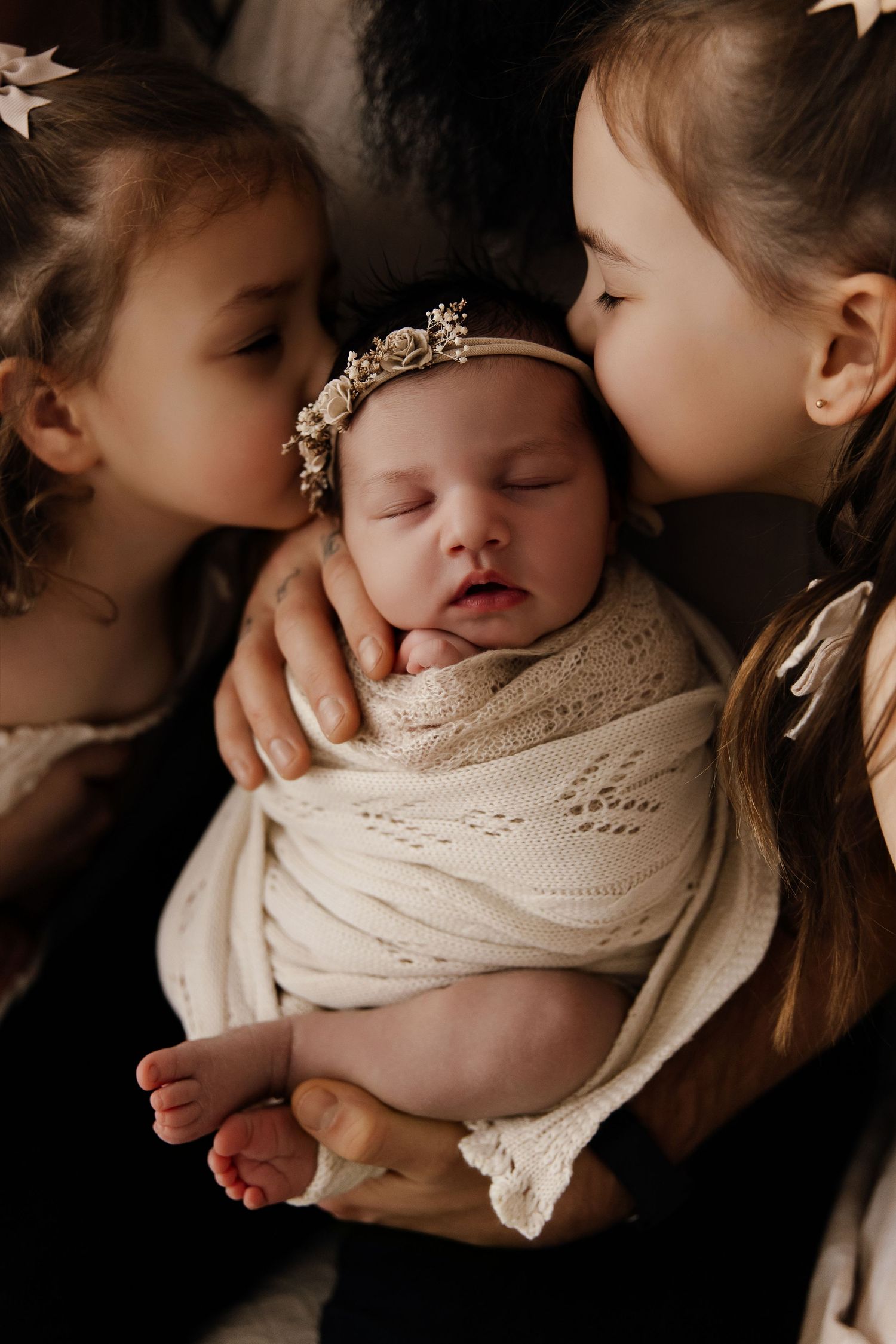 A series of intimate newborn photography shots showing gentle kisses and cuddles with a baby wrapped in cream knit fabric.