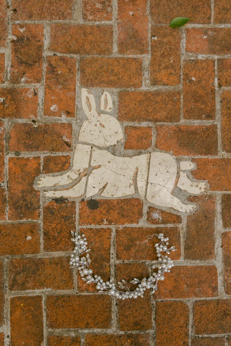 A whimsical white rabbit graffiti art piece stenciled on red brick wall with floral accents.