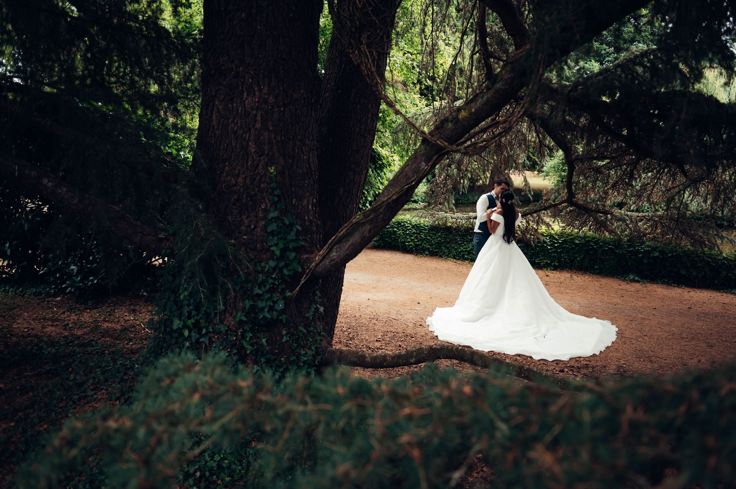 Mariée marchant dans un parc arboré avec sa robe traînante, photo de mariage en Bretagne.